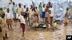 FILE - Burundian refugee children stand in the mud near to tents holding hundreds of other refugees who have fled from Burundi, at the Gashora refugee camp, in the Bugesera district of Rwanda, April 21, 2015.