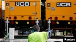 An employee loads lighting towers manufactured by JC Bamford Excavators Ltd. (JCB) at the the JCB France headquarters in Sarcelles, near Paris, France, May 22, 2017. 