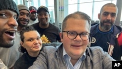 This image provided by Jonathan Franks shows Franks with six American prisoners detained by Kuwait as they pose for a photo at Kuwait International Airport, March 12, 2025, before flying home to the United States.