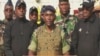 FILE - This video grab taken from a video obtained by AFPTV from Gabon 24 on Aug. 30, 2023 shows Colonel Ulrich Manfoumbi Manfoumbi (C), spokesperson of the Committee for the Transition and Restoration of Institutions (CTRI), reading a statement on television.