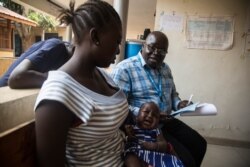 UNICEF health specialist Dr. Patti Samuel (R) explains the importance of childhood immunizations to a young mother. (Chika Oduah/VOA)