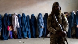 FILE - A Taliban fighter stands guard as women wait to receive food rations distributed by a humanitarian aid group, in Kabul, Afghanistan, Tuesday, May 23, 2023. (AP Photo/Ebrahim Noroozi, file)