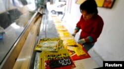 An employee arranges a shop window inside a bakery in a working-class neighborhood nearby downtown Santiago, Chile, Aug. 19, 2014. 