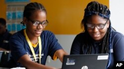 Jahiem Johnson, 13, kiri, membantu teman sekelas Kamya Saunders, 13, ketika mereka mengerjakan bagian bahasa Inggris selama kelas di Akademi Kepemimpinan Washington di Washington, 23 Agustus 2017. (Foto: AP)