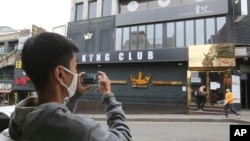 A man wearing a face mask takes pictures of a temporary closed dance club in Seoul, South Korea, Sunday, May 10, 2020. South Korea on Friday advised nightclubs and similar entertainment venues to close for a month.