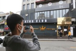 A man wearing a face mask takes pictures of a temporary closed dance club in Seoul, South Korea, May 10, 2020.