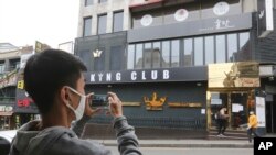 A man wearing a face mask takes pictures of a temporary closed dance club in Seoul, South Korea, May 10, 2020. 