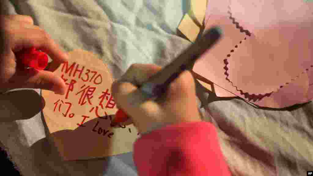 A girl writes a note which she will hang on a memorial for the people on Flight MH370 in Kuala Lumpur, March 30, 2014.