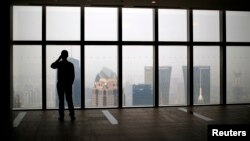 A man talks on a mobile phone as he looks at the view of the Shanghai skyline,