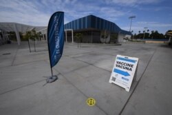 FILE - A sign points to a COVID-19 vaccination clinic offering the Pfizer vaccine to anyone over the age of 12, at Crenshaw High School in the traditionally Black and Latino neighborhood of South Los Angeles, July 8, 2021. The clinic was empty.