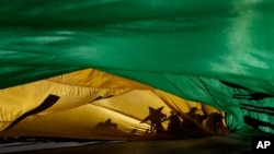 ស្រមោល​នៃ​ក្រុម​បាតុករ​នៅ​លើ​ទង់ជាតិ​នៃ​ប្រទេស​ប្រេស៊ីល​ក្នុង​អំឡុង​ពេល​ការតវ៉ា​ទាមទារ​ឲ្យ​មាន​ការចោទ​ប្រកាន់​ប្រធានាធិបតី​ប្រេស៊ីល Jair Bolsonaro ក្នុង​ក្រុង Brasilia ប្រទេស​ប្រេស៊ីល កាលពី​ថ្ងៃទី២៤ ខែកក្កដា ឆ្នាំ២០២១។