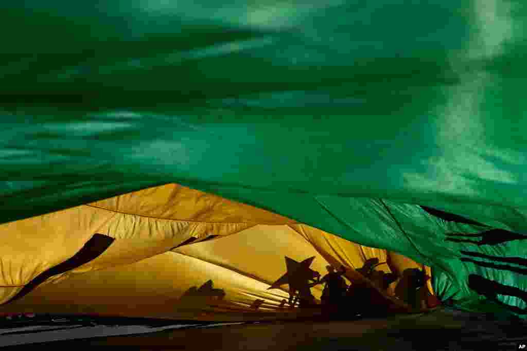 The shadows of demonstrators are cast on a Brazilian flag during a protest demanding the impeachment of Brazilian President Jair Bolsonaro in Brasilia, Brazil, July 24, 2021.
