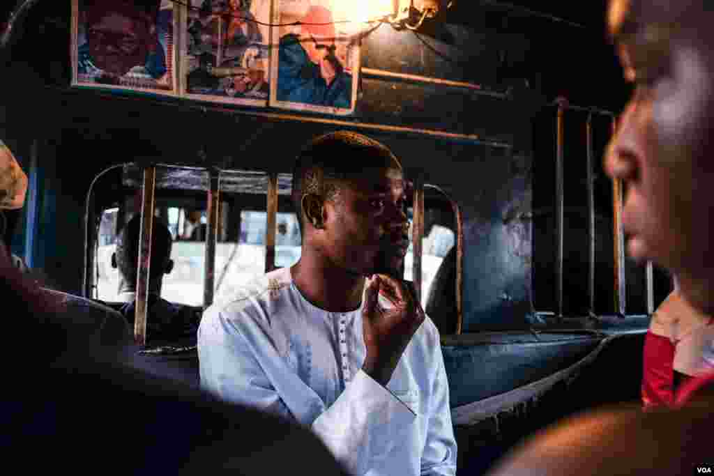 A passenger sits below a photo of a local religious leader. Drivers and owners decorate minibuses with photos of these 'marabouts,' reflecting which Muslim brotherhood they belong to in Senegal. (R. Shryock/VOA)