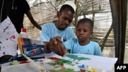 Un homme aide un enfant autiste à peindre lors de la Journée mondiale de l'autisme, à Abidjan le 2 avril 2017 (Photo d'illustration)