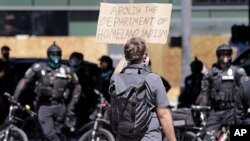 Një protestues mban një parrullë kundër forcave federale në Seattle