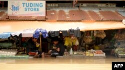 Vendors eat their lunch as they wait for customers at a flooded market in Candaba, Pampanga, north of Manila, Dec. 18, 2015. 