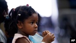 Skyler Lawson, 4, holds her mask as she waits with her family to board buses to evacuate Lake Charles, La., Aug. 26, 2020, ahead of Hurricane Laura.