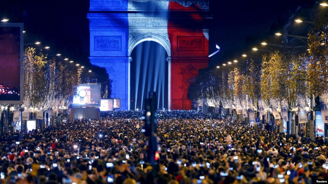 Warga Paris menghadiri perayaan tahun baru di Arc de Triomphe, yang diterangi cahaya lampu berwarna bendera Perancis Kamis malam (31/12).