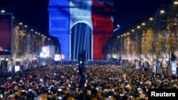 Warga Paris menghadiri perayaan tahun baru di Arc de Triomphe, yang diterangi cahaya lampu berwarna bendera Perancis Kamis malam (31/12).