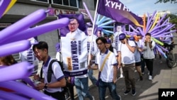 Supporters walk holding posters of HUN party parliamentary candidates on a street in Ulaanbaatar, Mongolia, on June 24, 2024, ahead of the parliamentary elections on June 28.