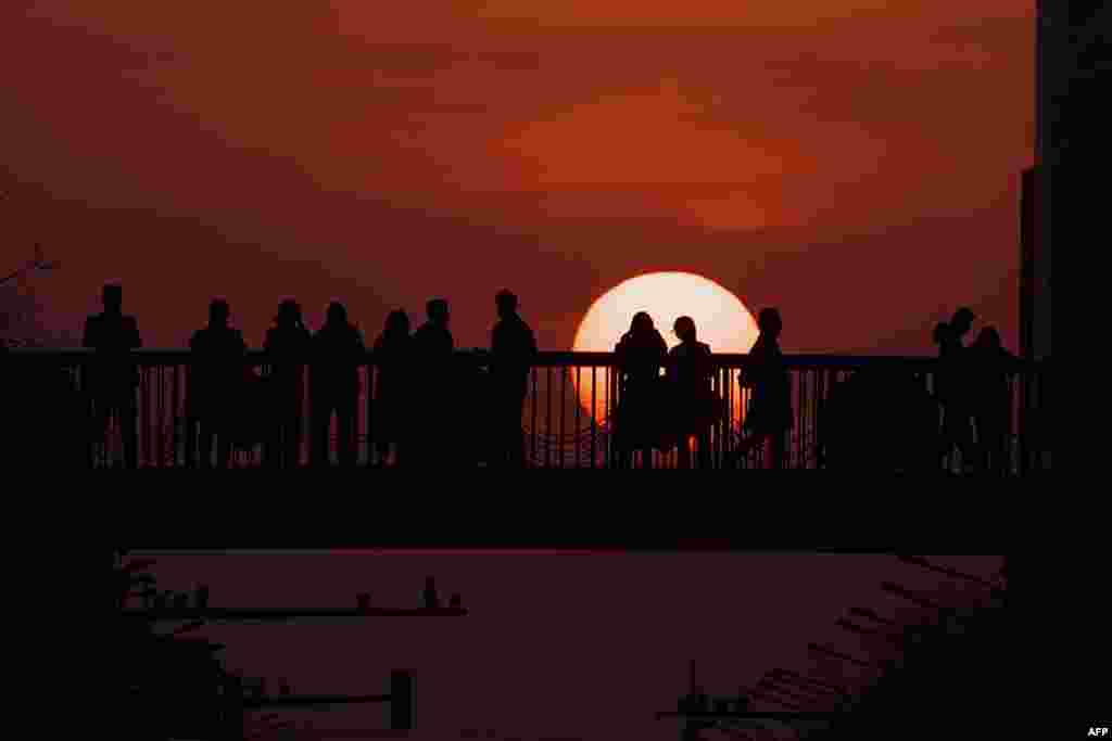 People watch the sunset from an overpass in Beijing, China.