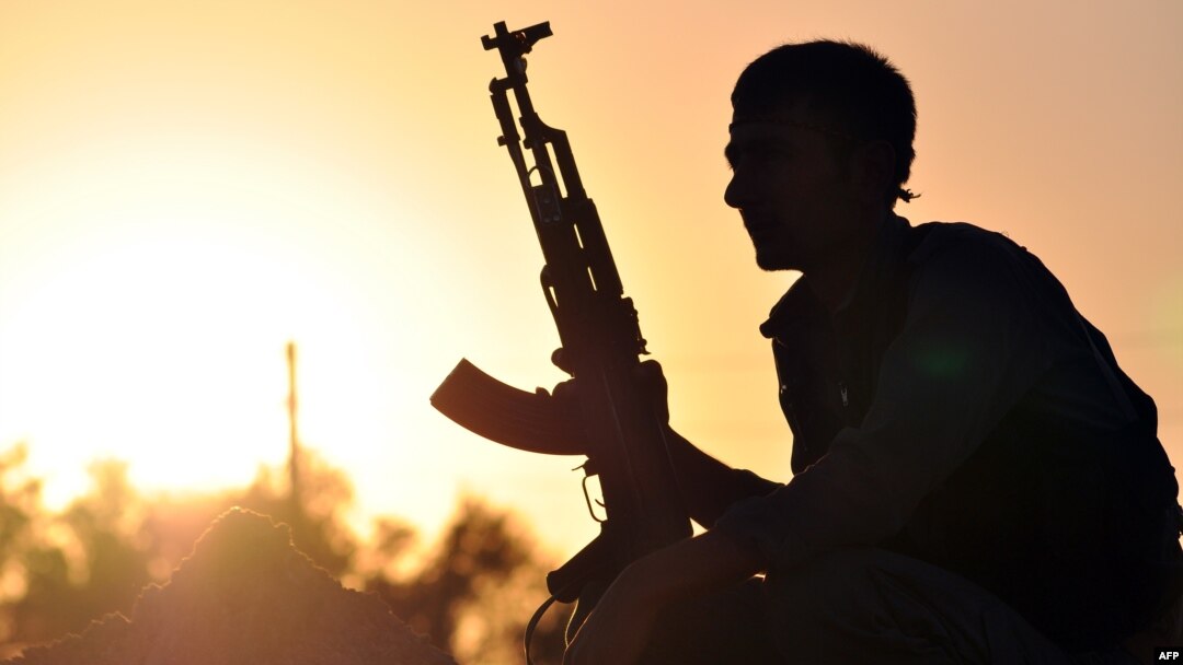 A fighter from the Kurdish People Protection Unit (YPG) is photographed at sunset in the Syrian town of Ain Issi, north of Raqqa during clashes between IS jihadists and YPG fighters, July 10, 2015. 