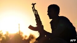 Một chiến binh người Kurd tạo dáng lúc mặt trời mọc tại thành phố Ain Issi của Syria, cách Raqqa khoảng 50 km về phía bắc.