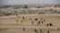 Iraqi citizens who fled the fighting between the Islamic State militants and the Iraqi forces, walk in front of destroyed houses on their way to receive aid supplies and clothes, in the Samah front line neighborhood, in Mosul, Iraq, Nov. 28, 2016. The off
