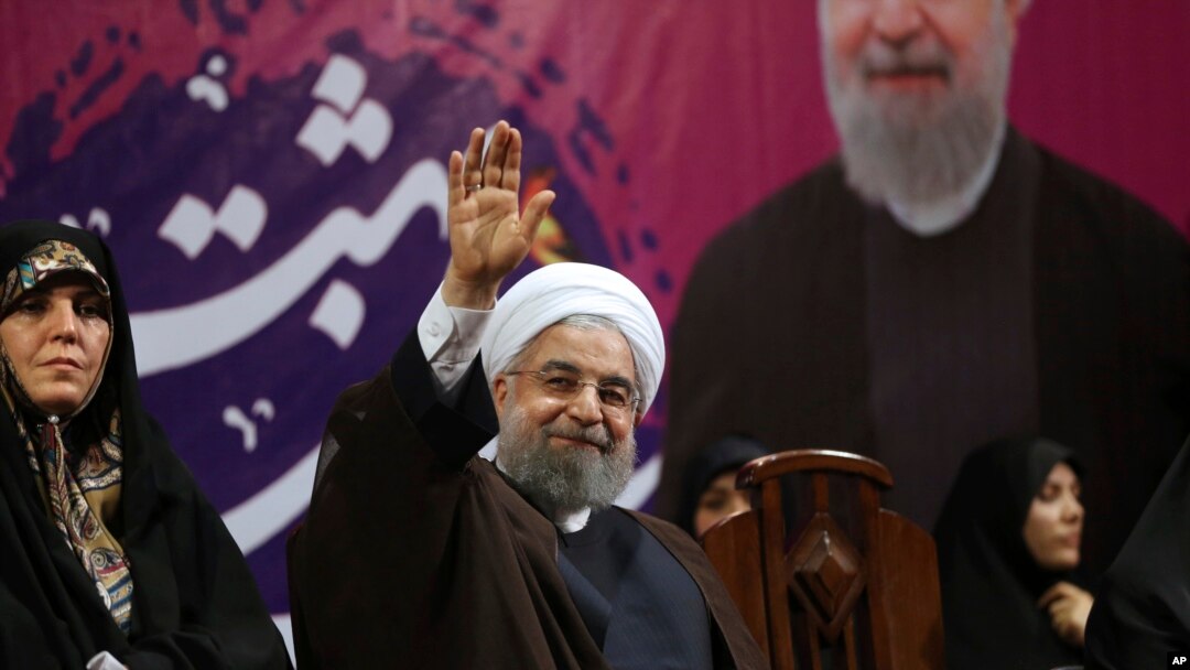 Iranian President Hassan Rouhani, center, waves to his supporters as he is accompanied by Vice President for Women and Family Affairs Shahindokht Molaverdi in a campaign rally for the May 19 presidential election in Tehran, Iran, May 9, 2017. 