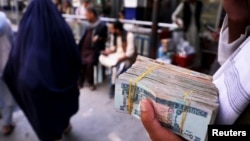 FILE - A person holds a bundle of Afghan afghani banknotes at a money exchange market, in Kabul, Afghanistan, Sept. 4, 2021.