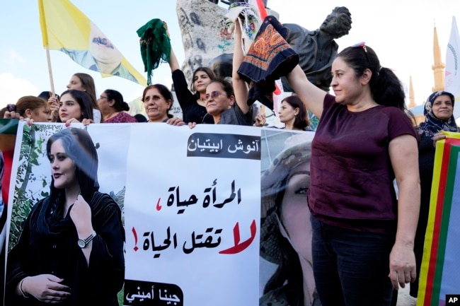 Kurdish women activists hold head coverings and a picture of Iranian woman Mahsa Amini, with Arabic that reads, "The woman is life, don't kill the life," during a protest against her death in Iran, at Martyrs' Square in downtown Beirut, September 21, 2022. (AP Photo/Bilal Hussein, File)