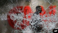 A security guard walks behind shattered glass at the CNN building at the CNN Center in the aftermath of a demonstration against police violence on Saturday, May 30, 2020, in Atlanta. (AP Photo/Brynn Anderson)