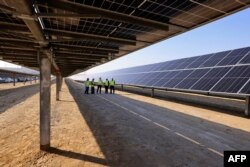 (FILES) Employees stand at the Al Dhafra Solar Photovoltaic (PV) Independent Power Producer project, in the United Arab Emirates' capital Abu Dhabi, during a visit by the French economy minister on January 31, 2023. Arab Gulf states are eyeing "green" hydrogen to transition their economies and ease the climate crisis.