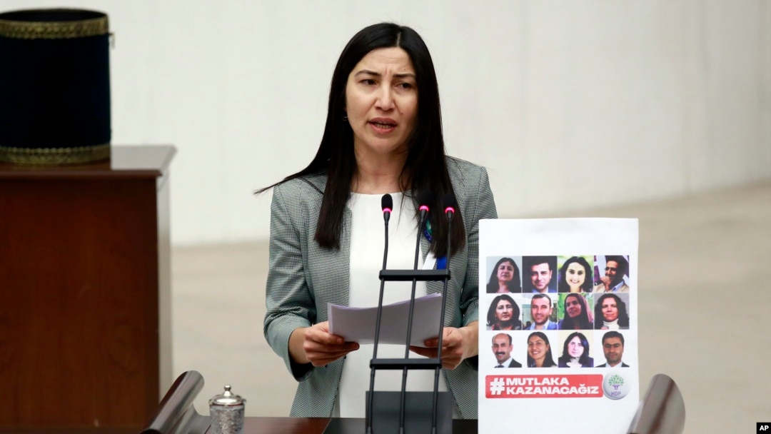 FILE - Leyla Birlik, a lawmaker from pro-Kurdish Peoples' Democratic Party, HDP, speaks next to a placard with photos of 11 jailed HDP lawmakers in Ankara, Turkey, Jan. 19, 2017.