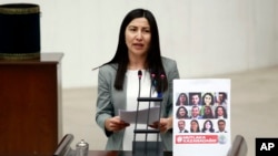 FILE - Leyla Birlik, a lawmaker from pro-Kurdish Peoples' Democratic Party, HDP, speaks next to a placard with photos of 11 jailed HDP lawmakers in Ankara, Turkey, Jan. 19, 2017.