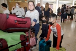 FILE - A woman and her children, wearing face masks, arrive in Sydney, Jan. 23, 2020, from a flight from Wuhan, China.