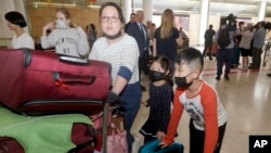 A woman and her children, wearing face masks, arrive in Sydney Thursday, Jan. 23, 2020, from a flight from Wuhan, China. 