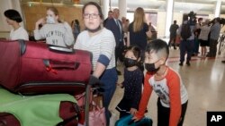 Seorang ibu dan dua anaknya (mengenakan masker) dari Wuhan, China, tiba di bandara Sydney, 23 Januari 2020. (Foto: dok).