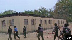 Des forces de sécurité à pied devant une école secondaire publique incendiée dans Chibok, Nigeria. 21 avril, 2014 (ARCHIVES).