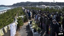 Les gens observent une minute de silence au japon, face à la mer à Hisanohama, préfecture de Fukushima le 11 mars 2021, marquant le 10e anniversaire du séisme de magnitude 9,0 qui a déclenché un tsunami et catastrophe nucléaire. (Photo de CHARLY TRIBALLEAU / AFP)