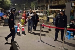 FILE - Residents walk past a security checkpoint at the close of a open air market in Kashgar in western China's Xinjiang region, Nov. 4, 2017. Authorities are using data-driven surveillance to impose a digital police state in Xinjiang.