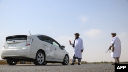 Taliban members of the Ministry for Propagation of Virtue and Prevention of Vice inspect vehicles at a checkpoint along a road on the outskirts of Herat province on October 4, 2024.