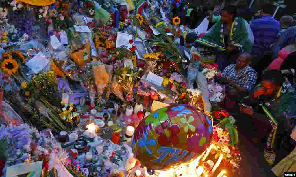 People pay tribute, lay flowers outside house where former South African President Nelson Mandela resided, Johanesburg, Dec. 7, 2013.