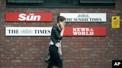 A woman speaks on her mobile phone outside the News International headquarters building that houses the top-selling newspaper The News of the World, which is closing, in east London, July 6, 2011