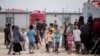 FILE - Women and children gather in front their tents at al-Hol camp, which houses 60,000 refugees, including families and supporters of the Islamic State group, many of them foreign nationals, in Hasakeh province, Syria, May 1, 2021.