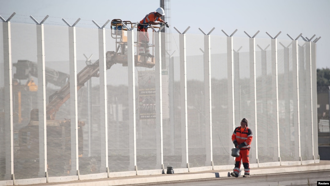 Các công nhân đặt dây thép gai trên một hàng rào dọc theo bến cảng Calais, Pháp, để ngăn chặn di dân nhảy từ xe tải, ngày 7 tháng 9 năm 2016. 