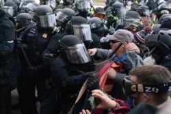 身着防暴装备的国会警察在1月6日的骚乱中，将一些试图冲入国会大厦的抗议者推回去。