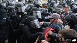 Petugas polisi Capitol dengan perlengkapan antihuru-hara mendorong mundur para demonstran yang mencoba mendobrak pintu Capitol AS pada hari Rabu, 6 Januari 2021, di Washington. (Foto: AP/Jose Luis Magana)