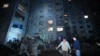 Local residents stand in the courtyard of a damaged residential building following a missile attack in Kharkiv late on Sept. 21, 2024. 