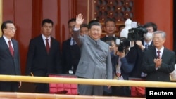 Chinese President Xi Jinping waves next to Premier Li Keqiang and former president Hu Jintao at the end of the event marking the 100th founding anniversary of the Communist Party of China, on Tiananmen Square in Beijing, July 1, 2021. 